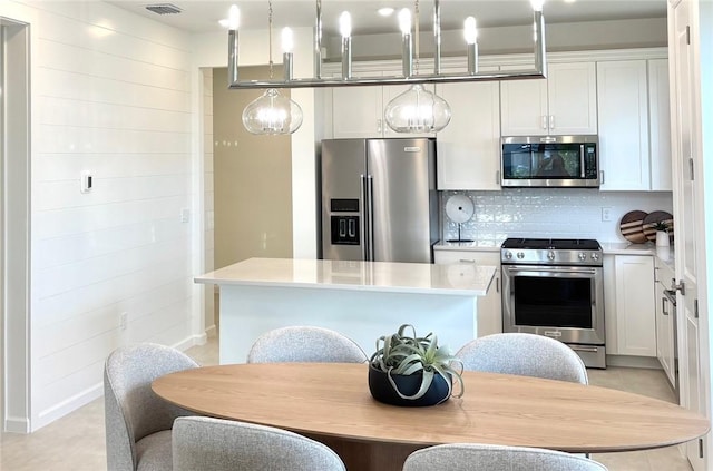 kitchen featuring stainless steel appliances, a center island, tasteful backsplash, light countertops, and decorative light fixtures