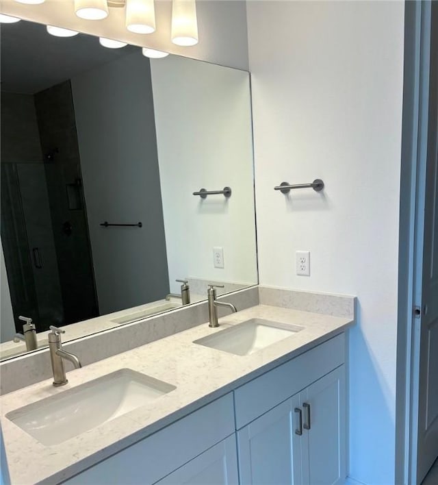 bathroom featuring double vanity, a stall shower, and a sink