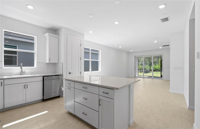 1223 Harper Way Unit 009, Vero Beach, FL 32960 - kitchen with stainless steel dishwasher, a sink, light tile patterned flooring, light countertops, and a center island