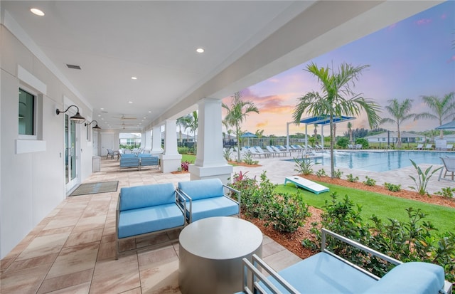patio terrace at dusk featuring a community pool