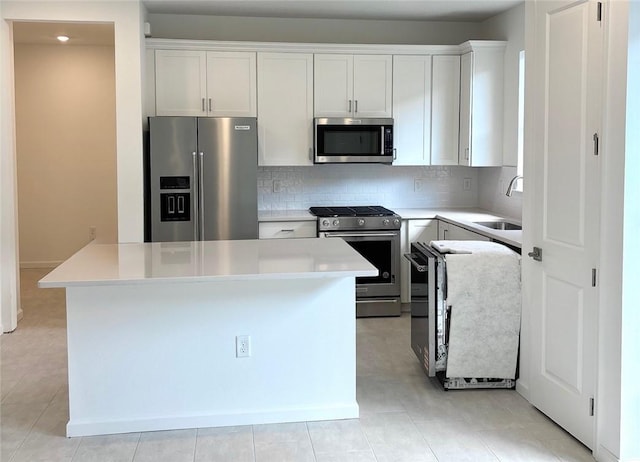 kitchen with tasteful backsplash, light countertops, stainless steel appliances, white cabinetry, and a sink