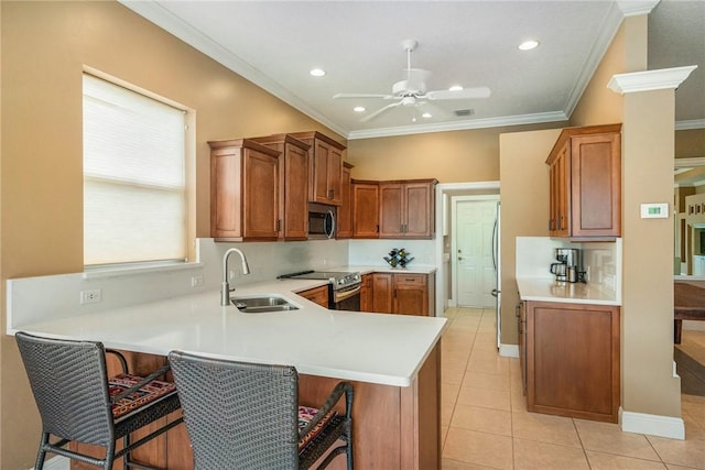 kitchen with a peninsula, light countertops, brown cabinets, appliances with stainless steel finishes, and a sink