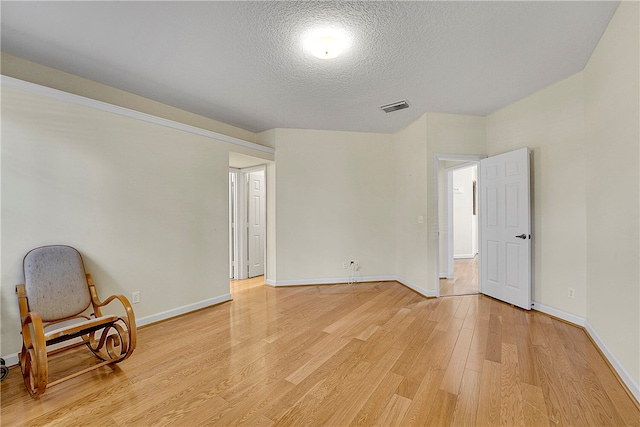 spare room with light hardwood / wood-style floors and a textured ceiling