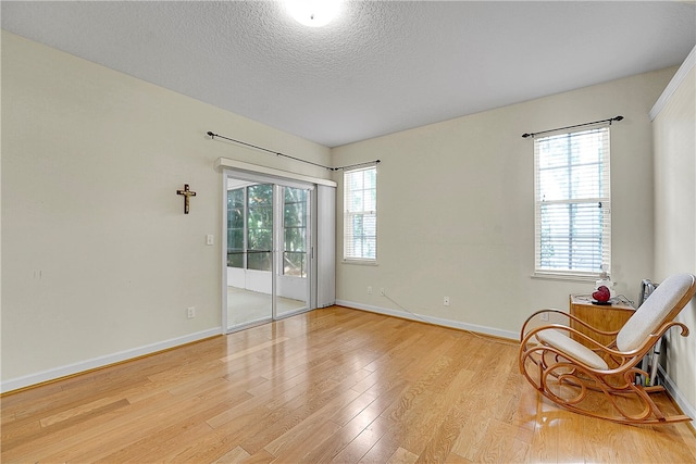 living area with a textured ceiling, a wealth of natural light, and light hardwood / wood-style floors