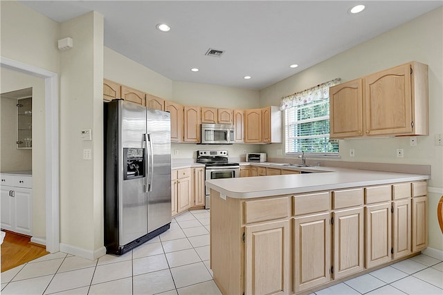 kitchen featuring stainless steel appliances, light brown cabinets, kitchen peninsula, and sink