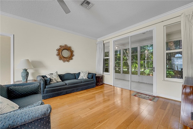 living room featuring ornamental molding, wood-type flooring, a textured ceiling, and ceiling fan