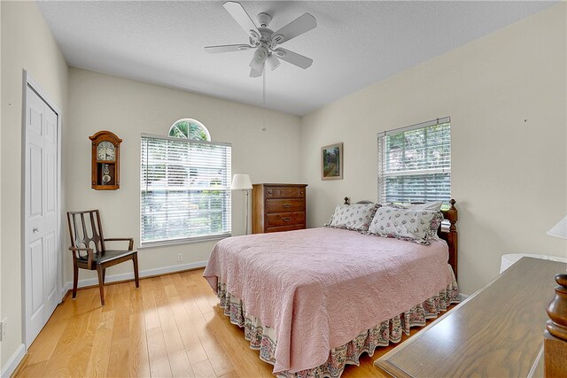 bedroom with a closet, multiple windows, ceiling fan, and light hardwood / wood-style flooring