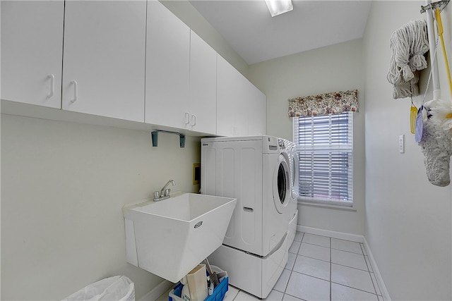 laundry area featuring washing machine and dryer, cabinets, sink, and light tile patterned floors