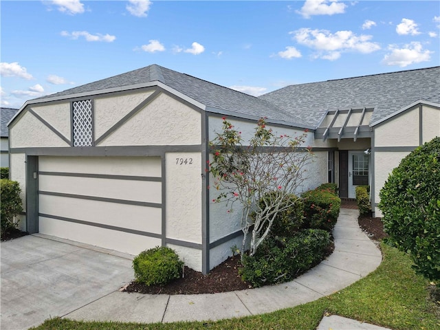 view of front of house with an attached garage, roof with shingles, concrete driveway, and stucco siding