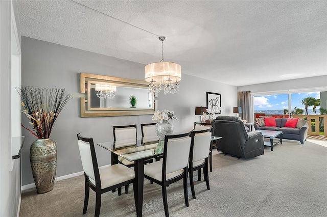 dining room featuring a chandelier, a textured ceiling, and carpet flooring