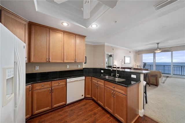 kitchen featuring sink, white appliances, dark stone countertops, a water view, and kitchen peninsula