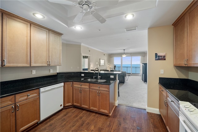 kitchen featuring sink, dark stone countertops, white appliances, and kitchen peninsula