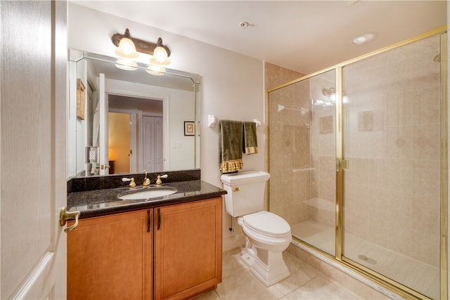 bathroom with a shower with door, vanity, tile patterned floors, and toilet