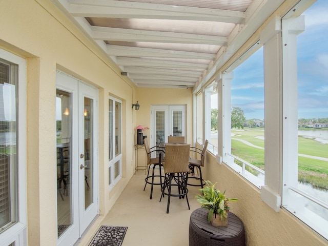 sunroom featuring beamed ceiling and a water view