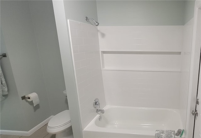 bathroom featuring baseboards, shower / bath combination, and toilet