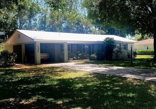 single story home featuring driveway, a front yard, and an attached carport