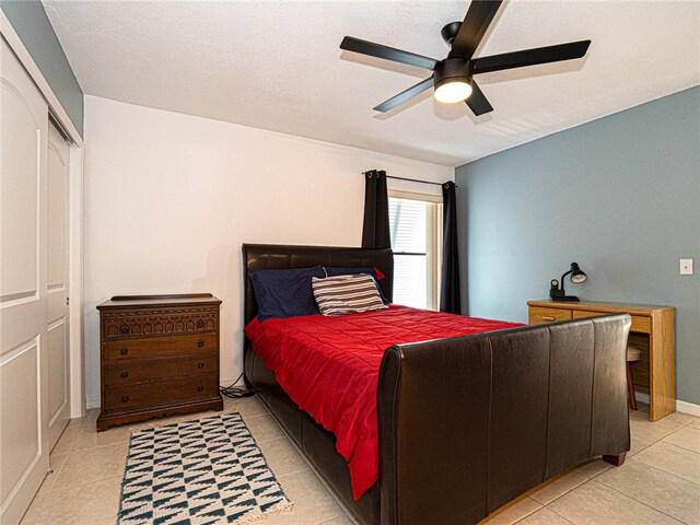 tiled bedroom with ceiling fan, a textured ceiling, and a closet