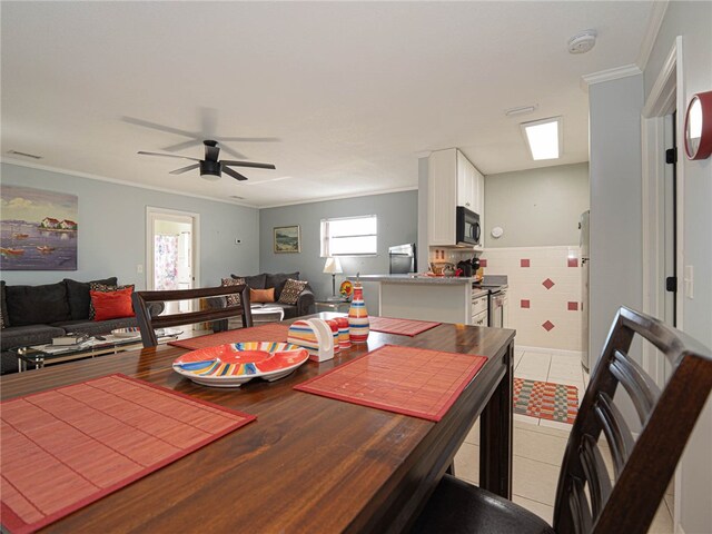 dining area featuring tile walls, ceiling fan, crown molding, and light tile patterned floors