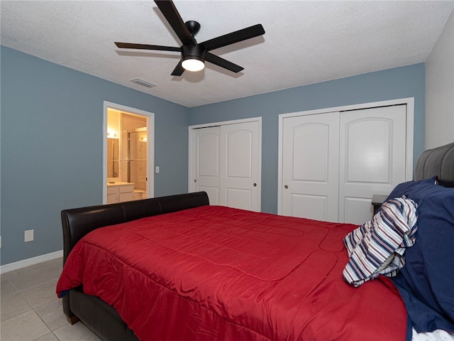 bedroom featuring multiple closets, a textured ceiling, light tile patterned floors, and ceiling fan