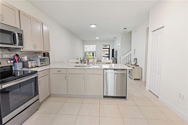 10011 W Villa Cir, Vero Beach, FL 32966 - kitchen with appliances with stainless steel finishes, a sink, a peninsula, light countertops, and decorative backsplash