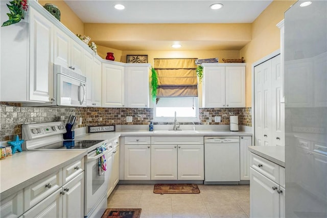 kitchen with light tile patterned flooring, sink, white cabinets, decorative backsplash, and white appliances