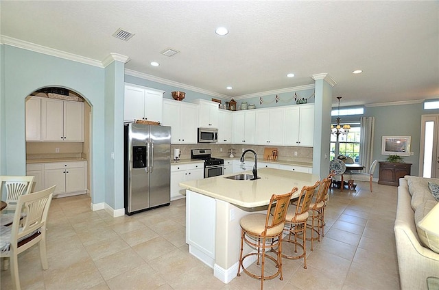 kitchen featuring white cabinetry, sink, an inviting chandelier, a center island with sink, and appliances with stainless steel finishes