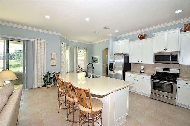 kitchen with sink, a breakfast bar area, decorative backsplash, a center island with sink, and appliances with stainless steel finishes