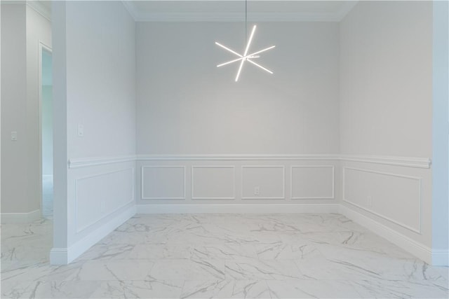 empty room with marble finish floor, a decorative wall, crown molding, and an inviting chandelier