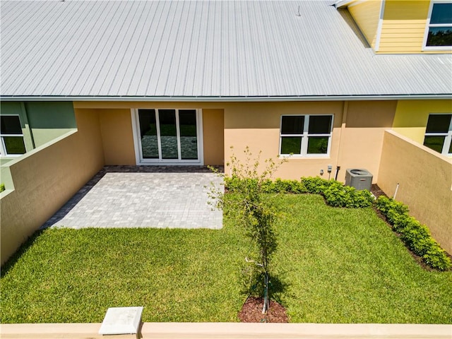 back of property featuring a lawn, a patio, metal roof, cooling unit, and stucco siding