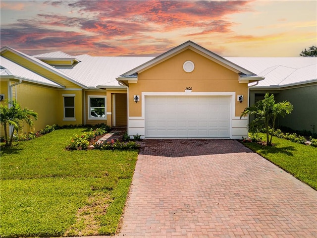 single story home with a garage, a front yard, decorative driveway, and stucco siding