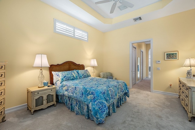 bedroom with a tray ceiling, light carpet, and ceiling fan