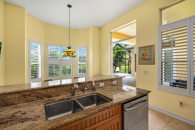 kitchen with dark stone counters, dishwasher, sink, light tile patterned flooring, and pendant lighting