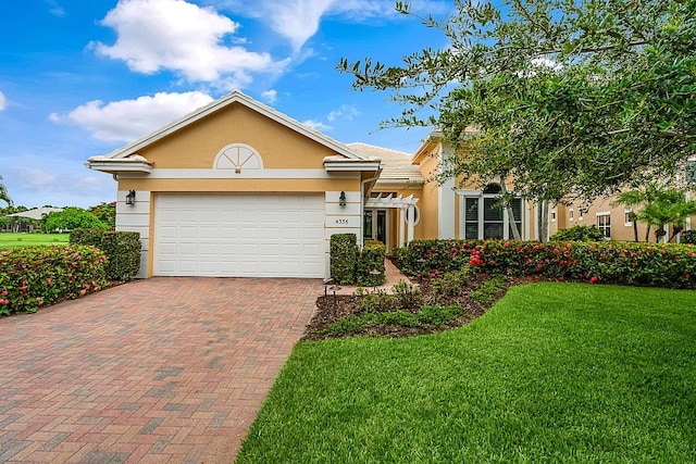 ranch-style home featuring stucco siding, decorative driveway, a garage, and a front lawn