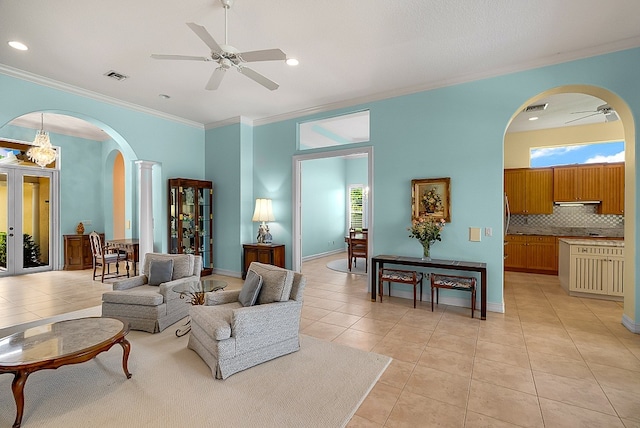 tiled living room with a high ceiling, ceiling fan, crown molding, and decorative columns