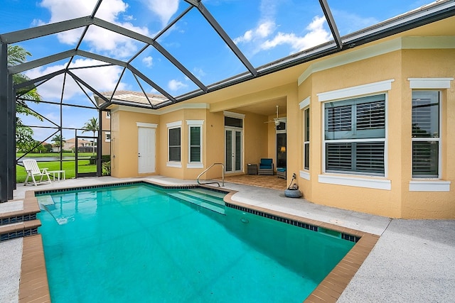 view of swimming pool with glass enclosure, a patio, and ceiling fan