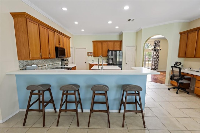 6029 Winfield Dr, Port St Lucie, FL 34986 - kitchen with black microwave, stainless steel fridge, a kitchen bar, and brown cabinetry