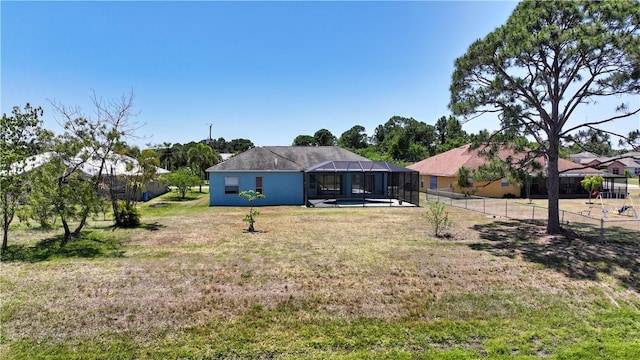 6029 Winfield Dr, Port St Lucie, FL 34986 - rear view of property featuring fence, glass enclosure, and a lawn