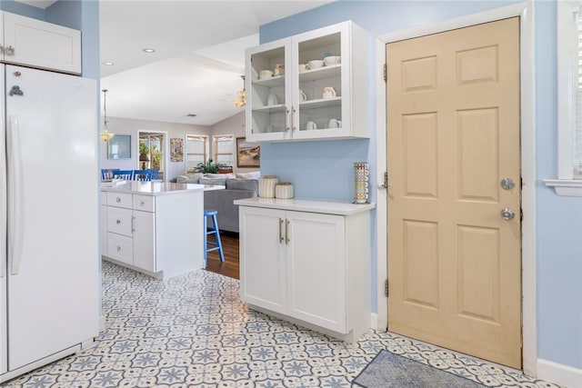 kitchen with white cabinets, kitchen peninsula, vaulted ceiling, and white fridge