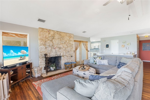 living room with a large fireplace, dark hardwood / wood-style flooring, ceiling fan, and radiator