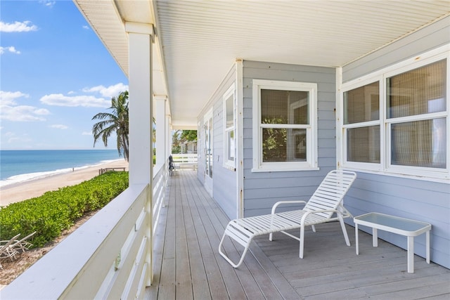 wooden deck featuring a water view and a beach view