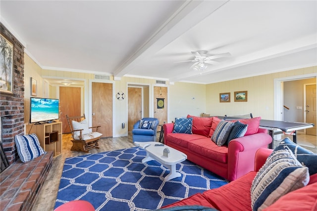 living room with wood-type flooring, ornamental molding, beam ceiling, wood walls, and ceiling fan