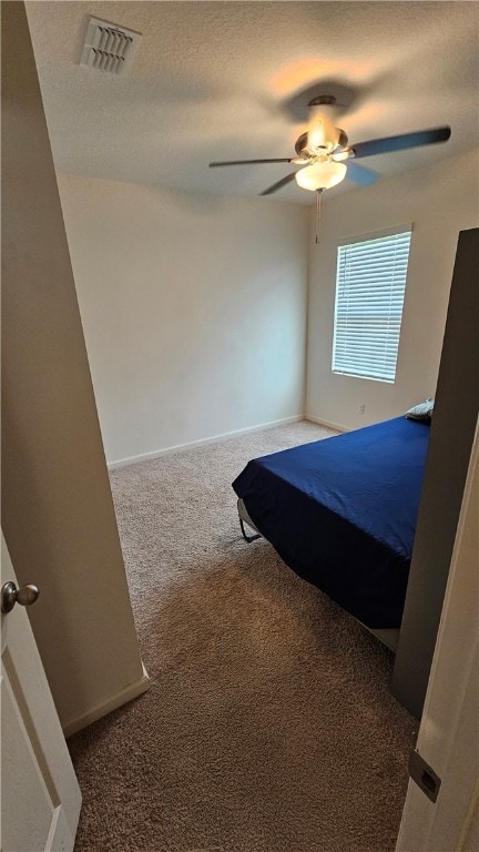 unfurnished bedroom with ceiling fan, a textured ceiling, and carpet flooring