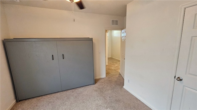 unfurnished bedroom featuring light colored carpet, ceiling fan, and a closet