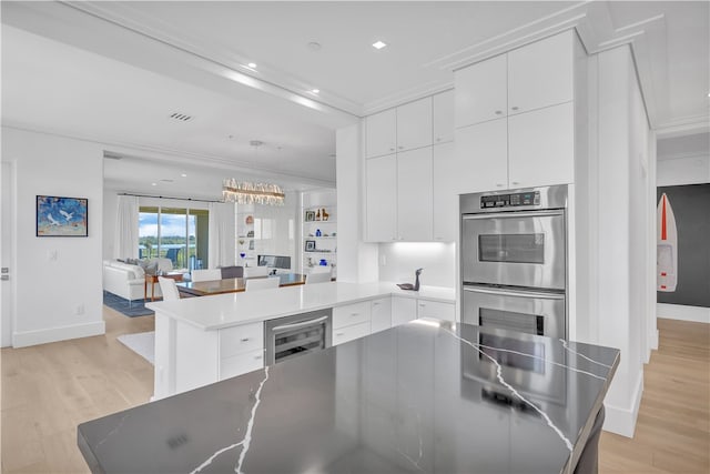 kitchen with light wood-type flooring, white cabinetry, double oven, and a center island