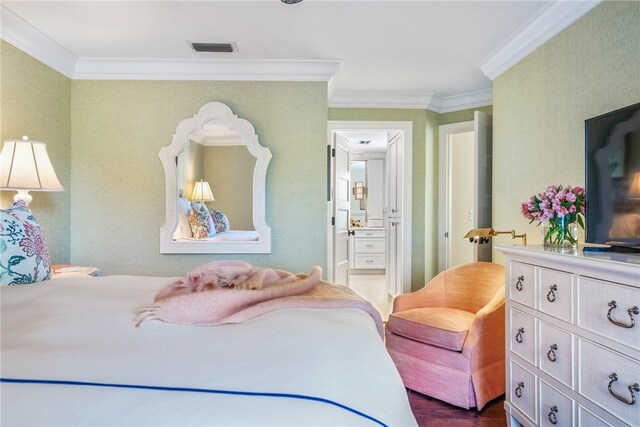 bedroom featuring hardwood / wood-style flooring, ensuite bath, and crown molding