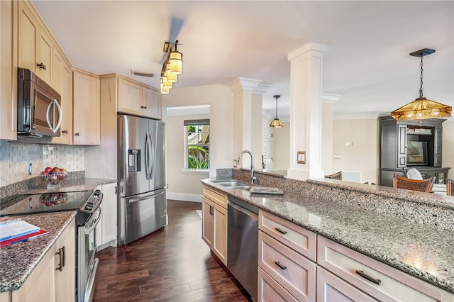 kitchen with stainless steel appliances, hanging light fixtures, sink, dark wood-type flooring, and decorative columns