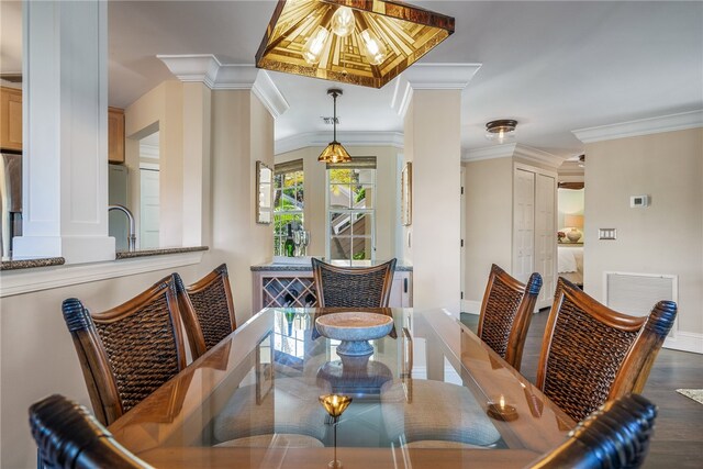 dining space with dark hardwood / wood-style floors, crown molding, decorative columns, and sink