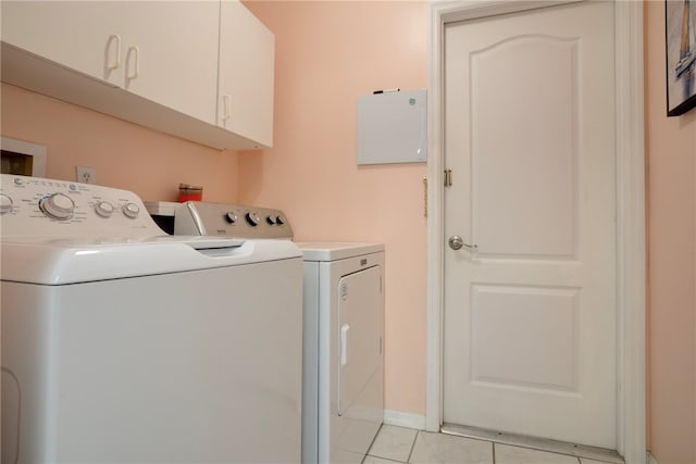 washroom featuring light tile patterned flooring, cabinets, and washing machine and clothes dryer