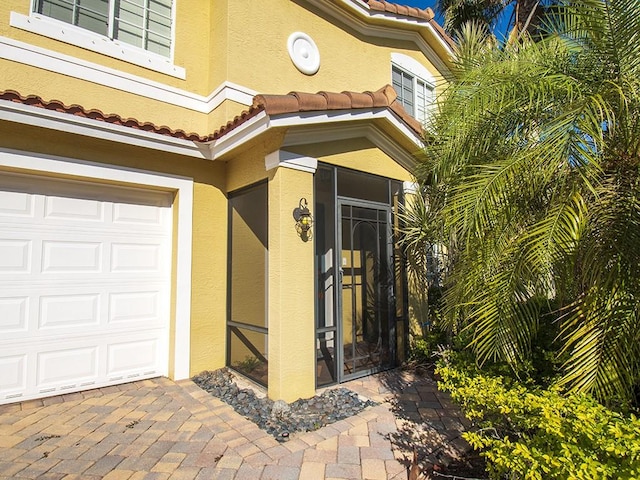 4368 56th Ln, Vero Beach, FL 32967 - doorway to property featuring stucco siding, a garage, and a tiled roof