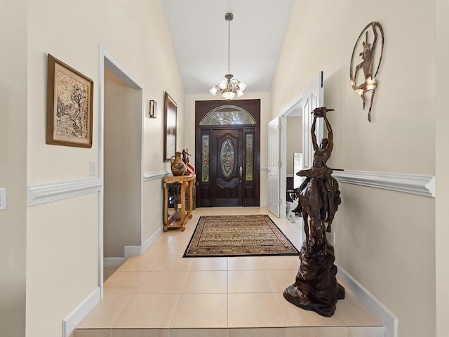 tiled foyer with vaulted ceiling and a notable chandelier